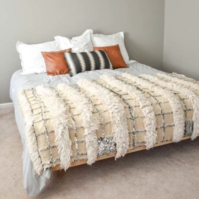 floating king bed with gray comforter white pillows leather pillows tribal pillow and moroccan wedding blanket
