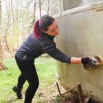 Sarah hand washing the vintage camper exterior
