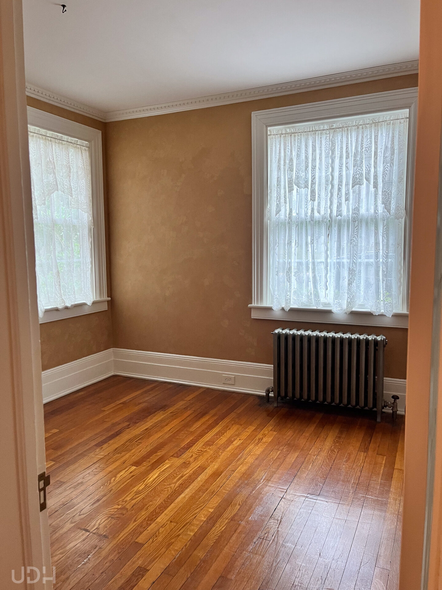 small room with brown Venetian plaster and radiator with lace curtains